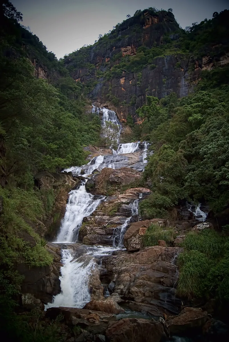 Ravana Falls cascading down a rock face surrounded by forest near Ella