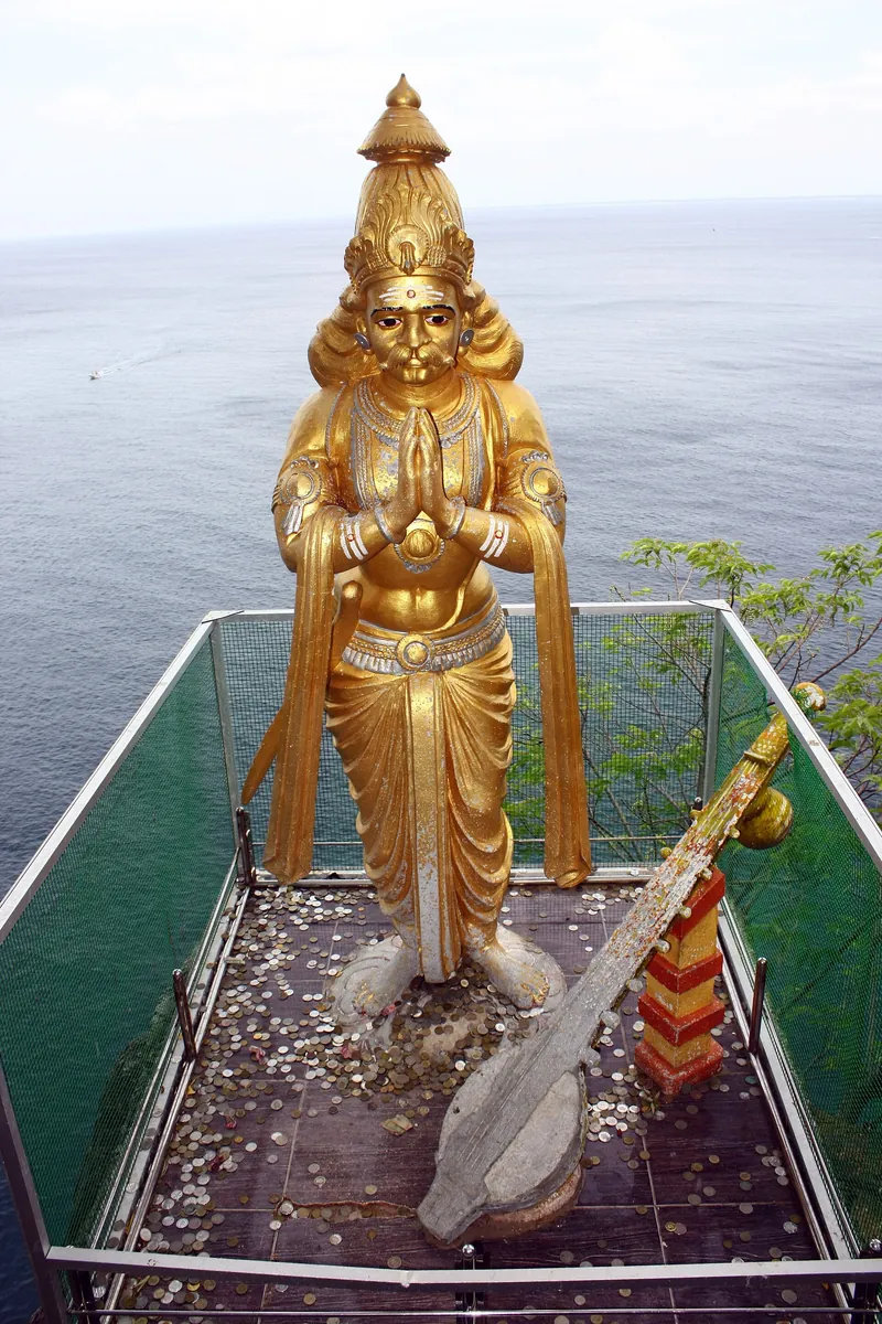 A golden statue of Ravana on the cliff at the Koneswaram temple in Trincomalee, with the sea behind